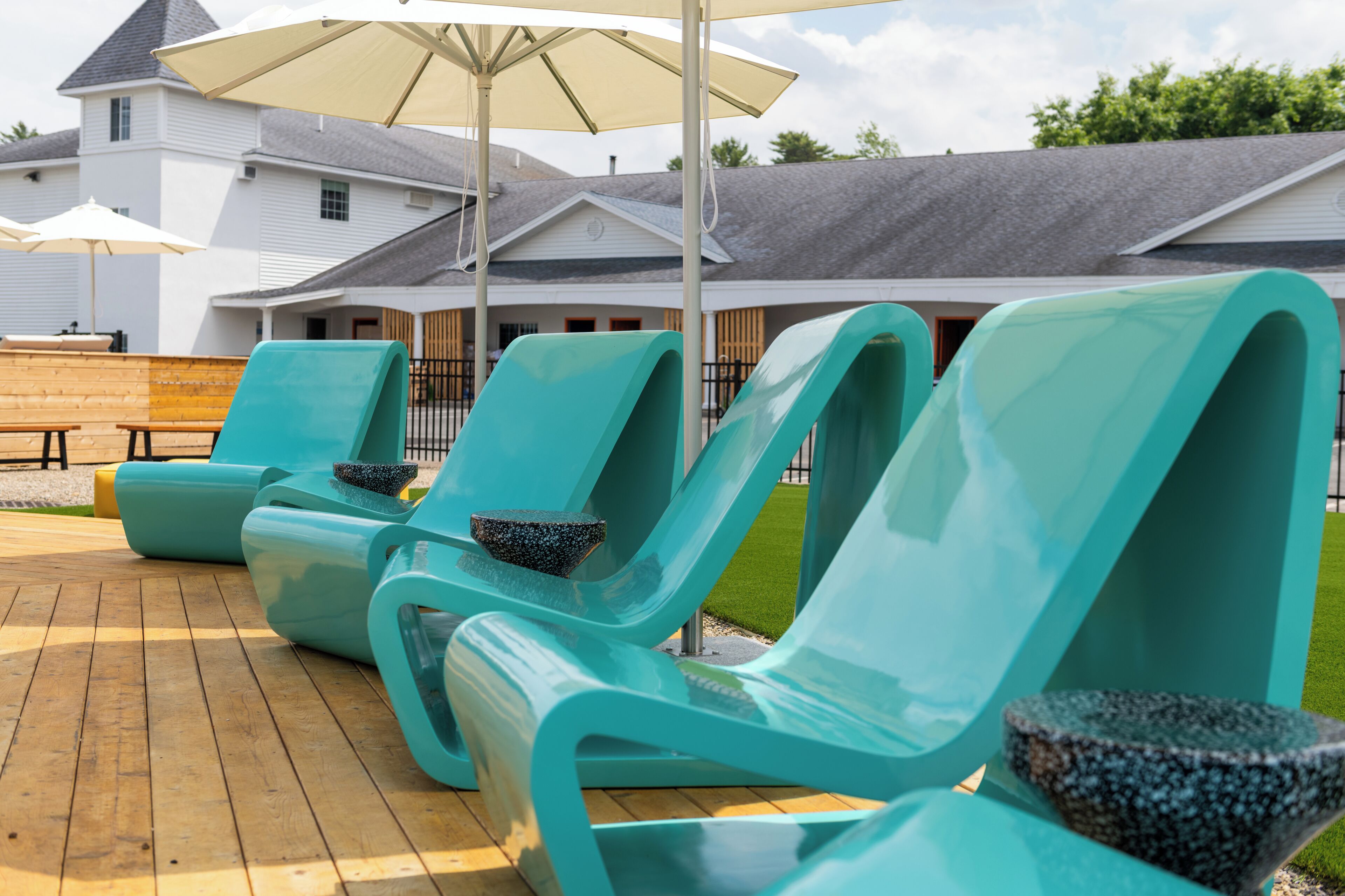 Outdoor lounge chairs with a stone bowl, a wooden bench, and a large umbrella.