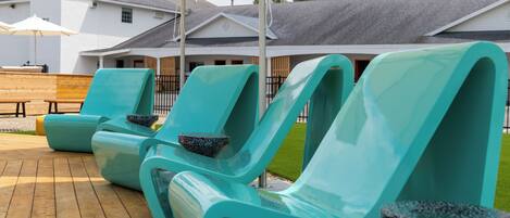 Outdoor lounge chairs with a stone bowl, a wooden bench, and a large umbrella.