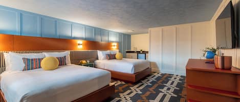 A hotel room with two beds, a wooden dresser, a TV, and a patterned carpet.