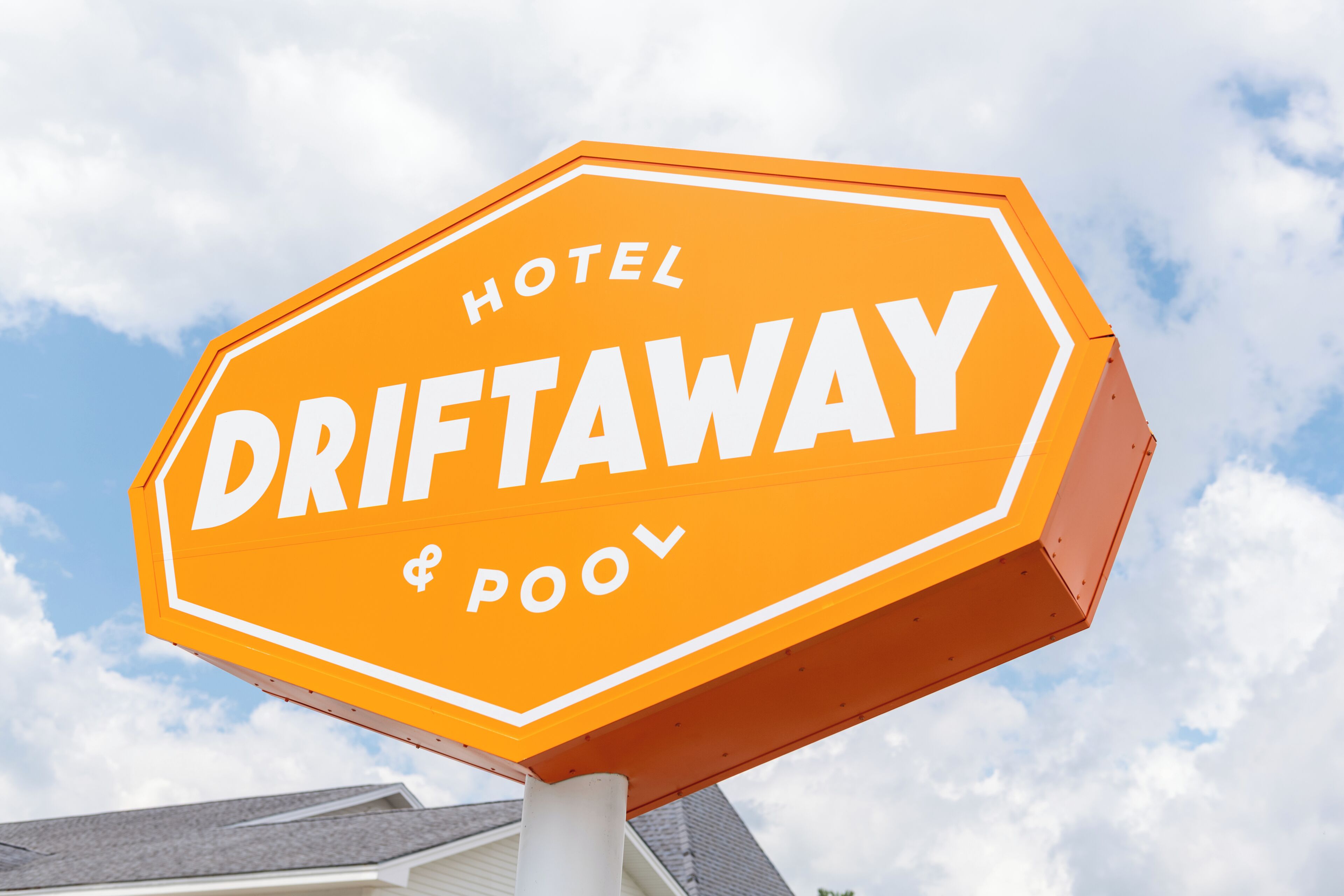 A hexagonal sign with the words 'HOTEL DRIFTAWAY & POOL' in white letters on an orange background.