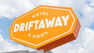 A hexagonal sign with the words 'HOTEL DRIFTAWAY & POOL' in white letters on an orange background.
