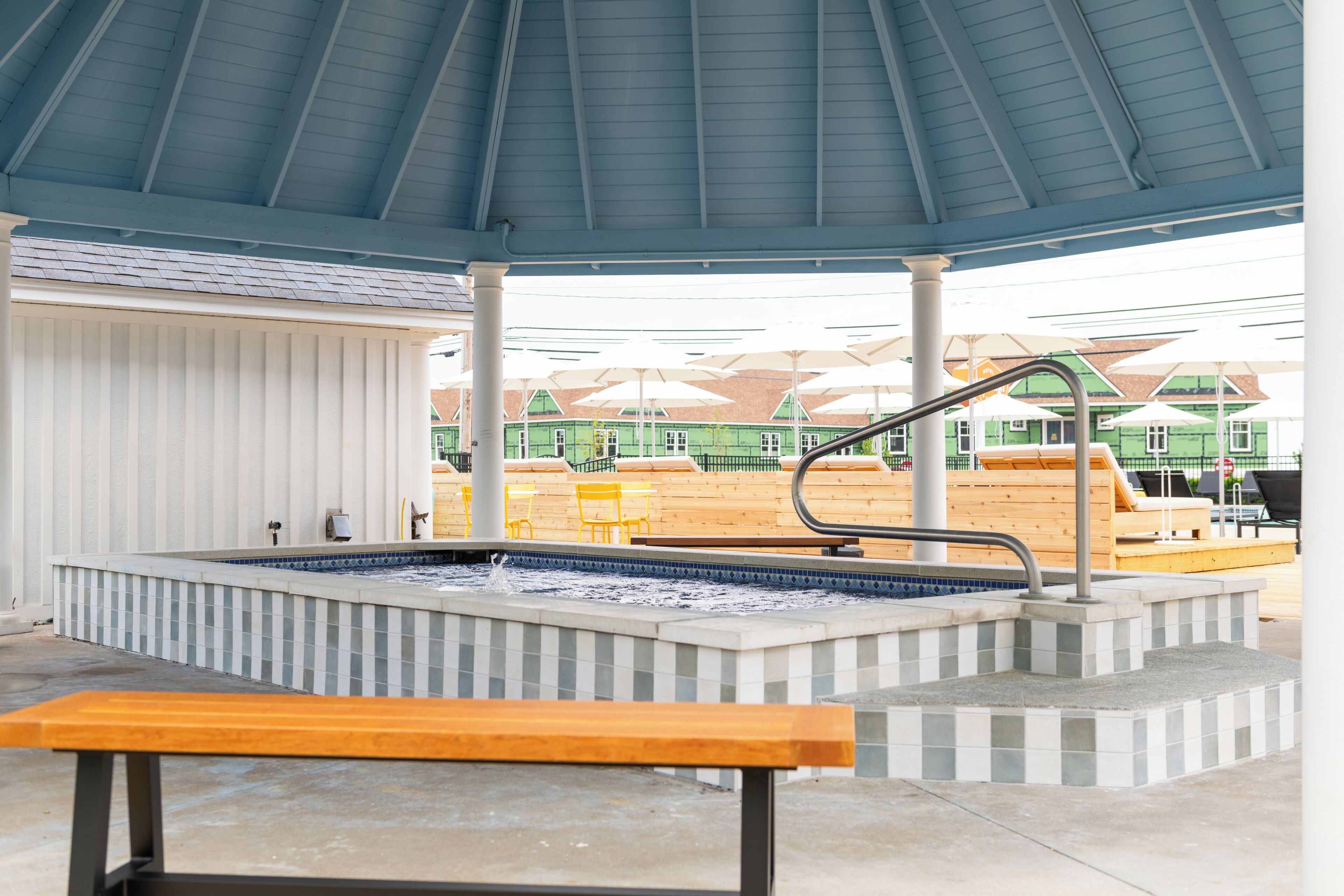 Un espace extérieur abrité avec une piscine, un banc, une fontaine et des parasols en arrière-plan.