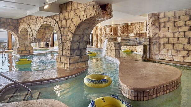 An indoor swimming pool with artificial rock walls and multiple inflatable tubes. - Island Vista Resort (Myrtle Beach)