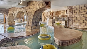 An indoor swimming pool with artificial rock walls and multiple inflatable tubes. - Island Vista Resort (Myrtle Beach)