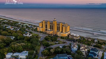 Un hotel grande y amarillo con múltiples torres, situado cerca de una playa y vistas al océano.