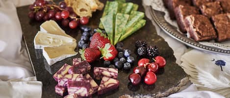 Een kaasplank met verschillende kazen, fruit en brood.