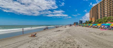 A beach with a hotel in the background.