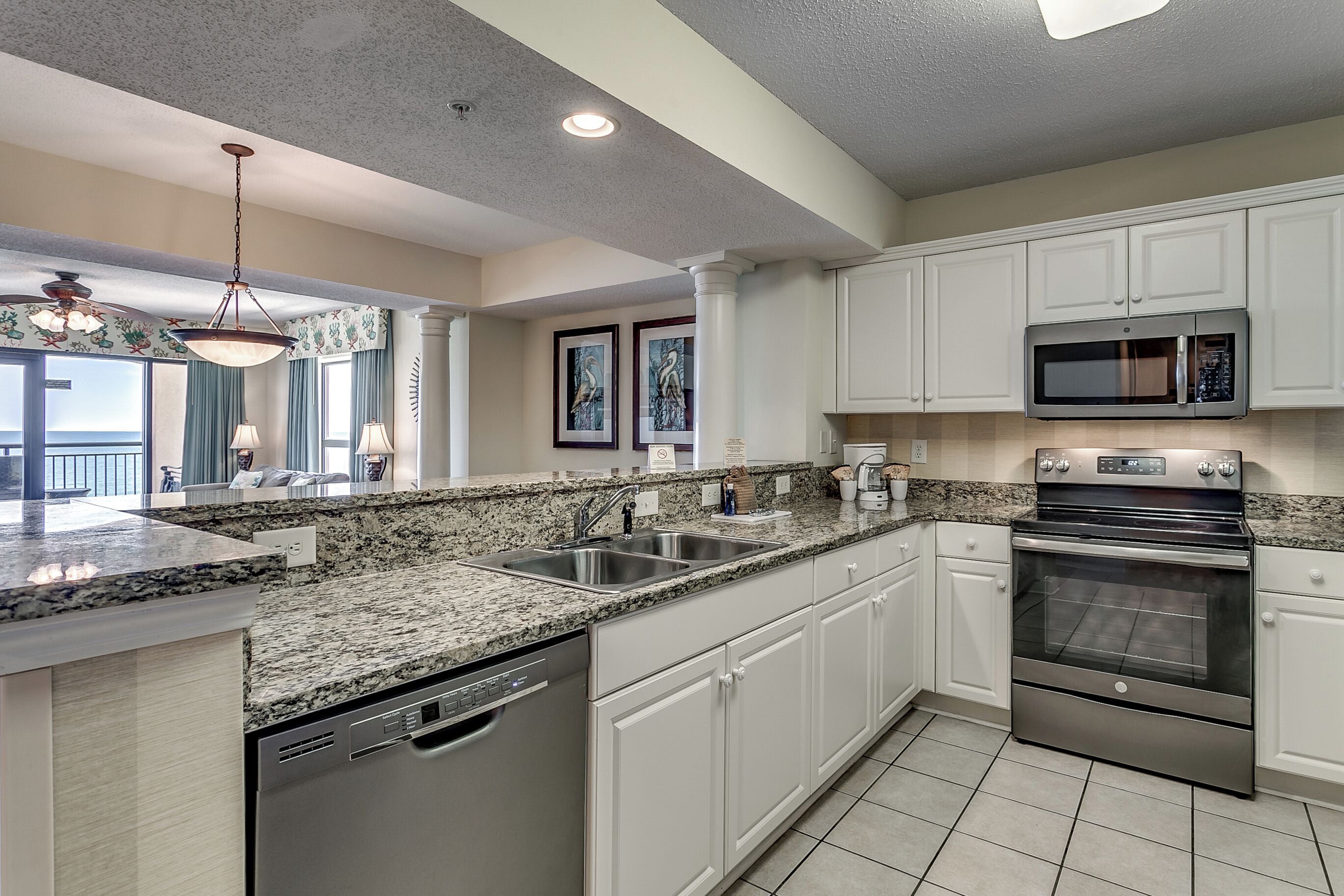A modern kitchen with white cabinets, granite countertops, stainless steel appliances, and a dishwasher.