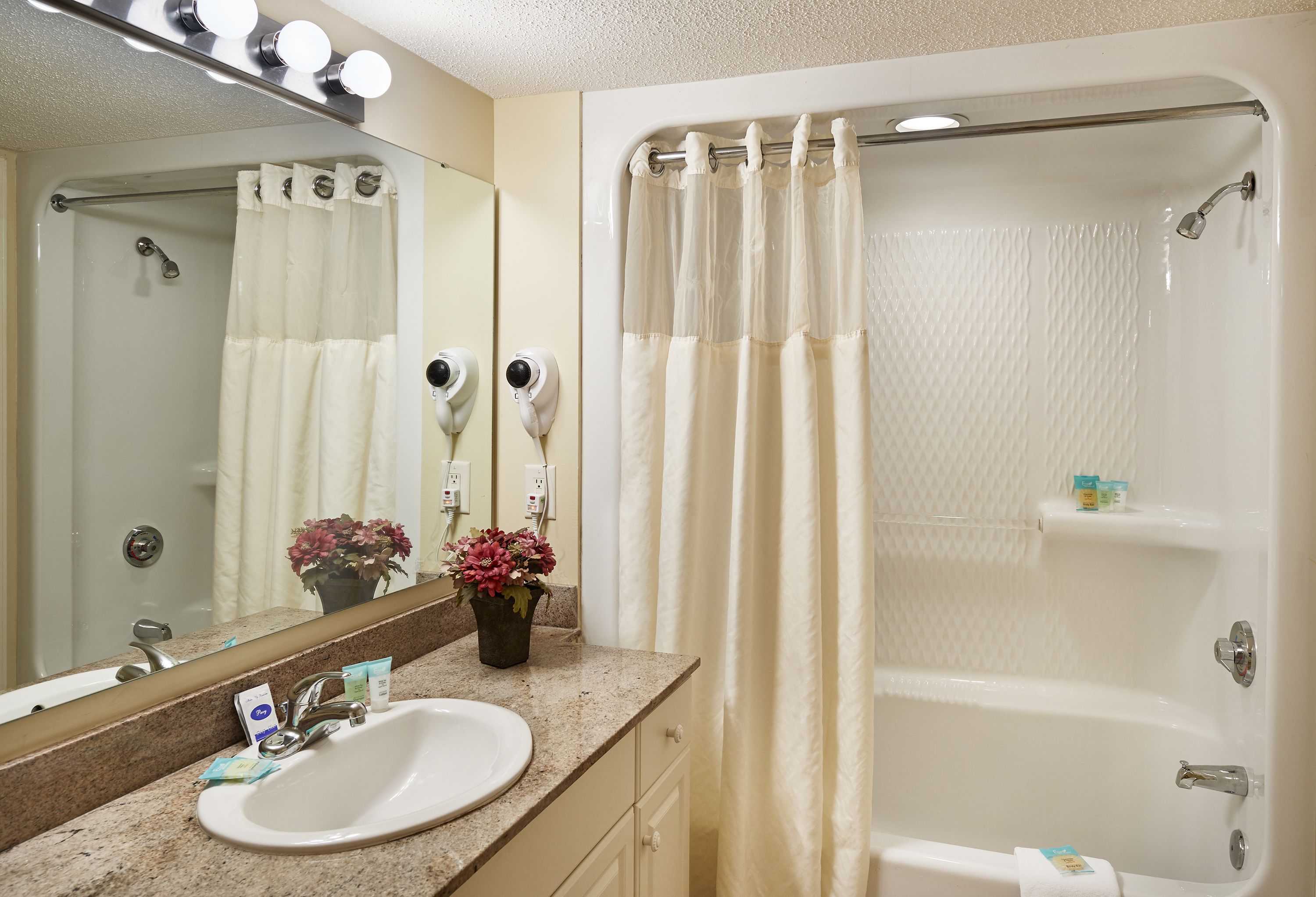 A bathroom with a sink, mirror, shower, and a towel rack.