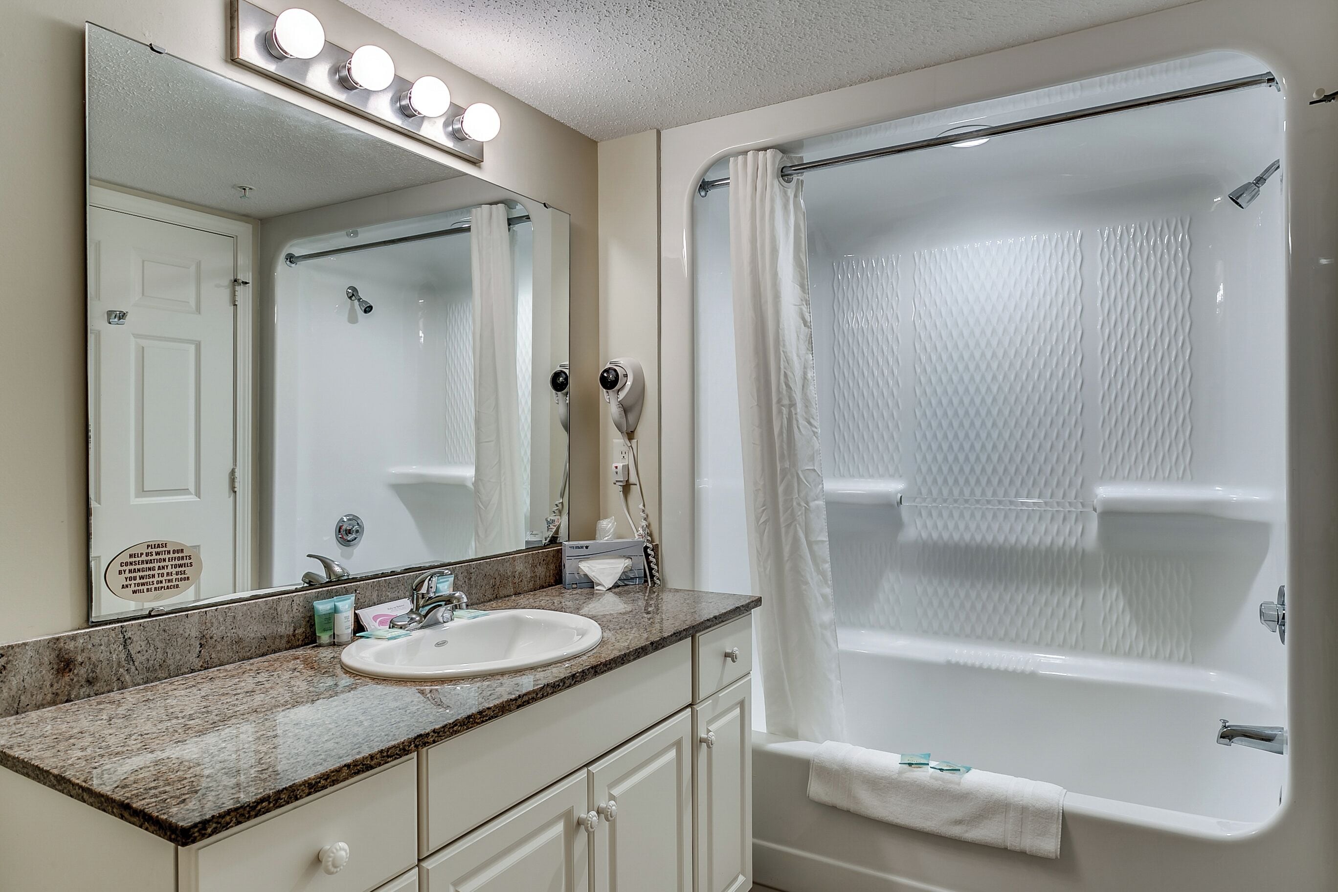 A bathroom with a sink, mirror, and shower.