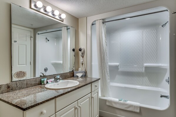 A bathroom with a sink, mirror, and shower.