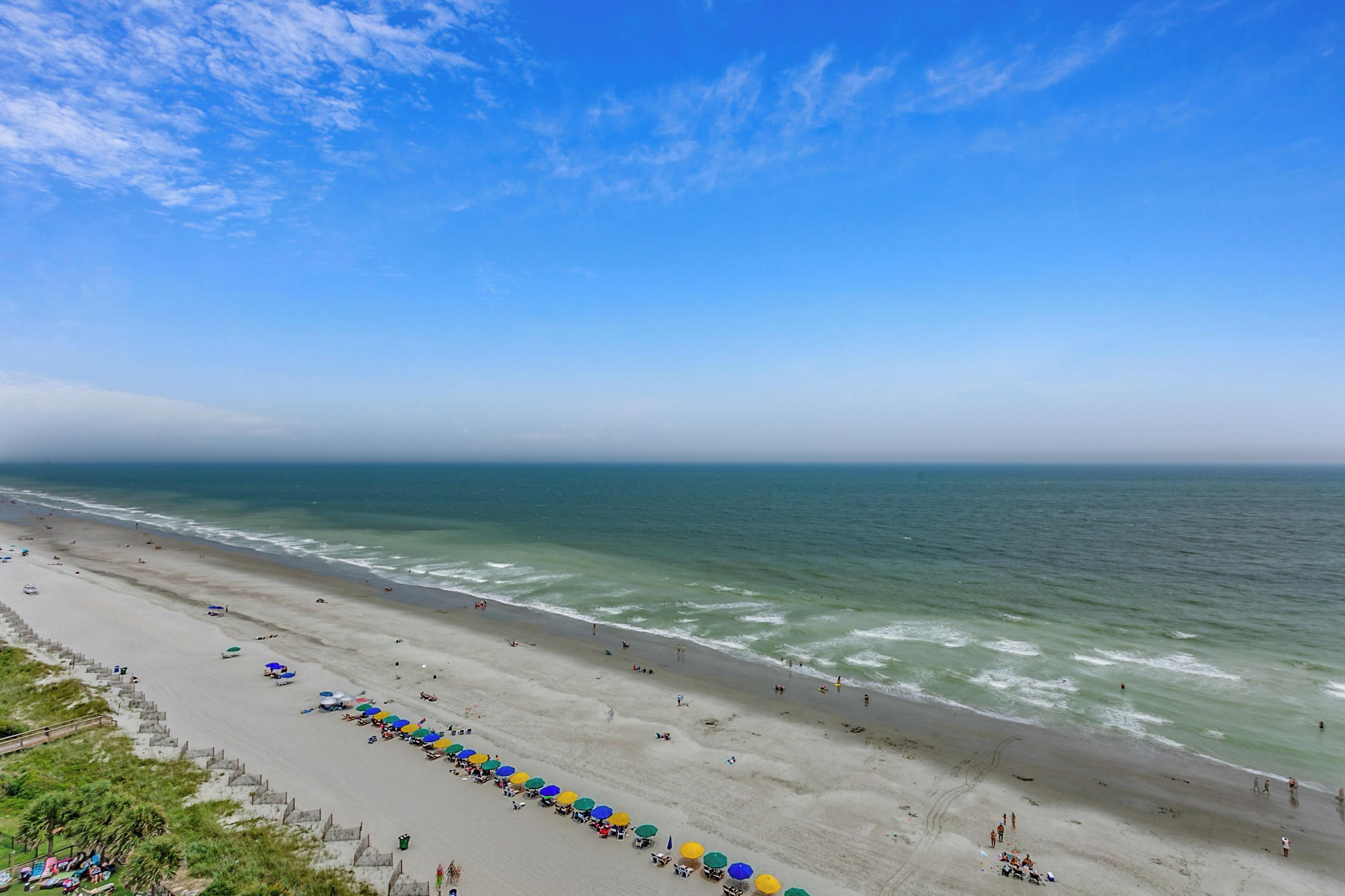A beach with umbrellas and people.