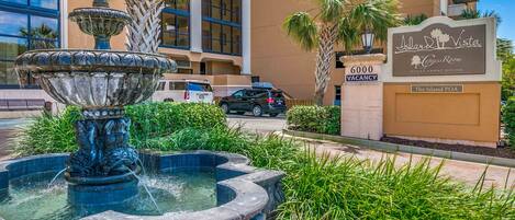 A fountain, palm trees, and a building with a sign for 'Island Vista Ocean Front Dining'.