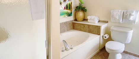 A bathroom with a bathtub, toilet, and a shelf with towels and a plant.