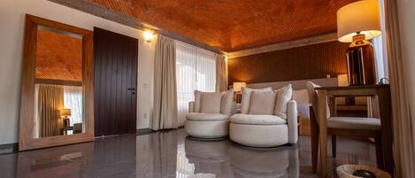 A modern interior with a polished floor, a seating area with two armchairs and a sofa, a wooden table, and a lamp.