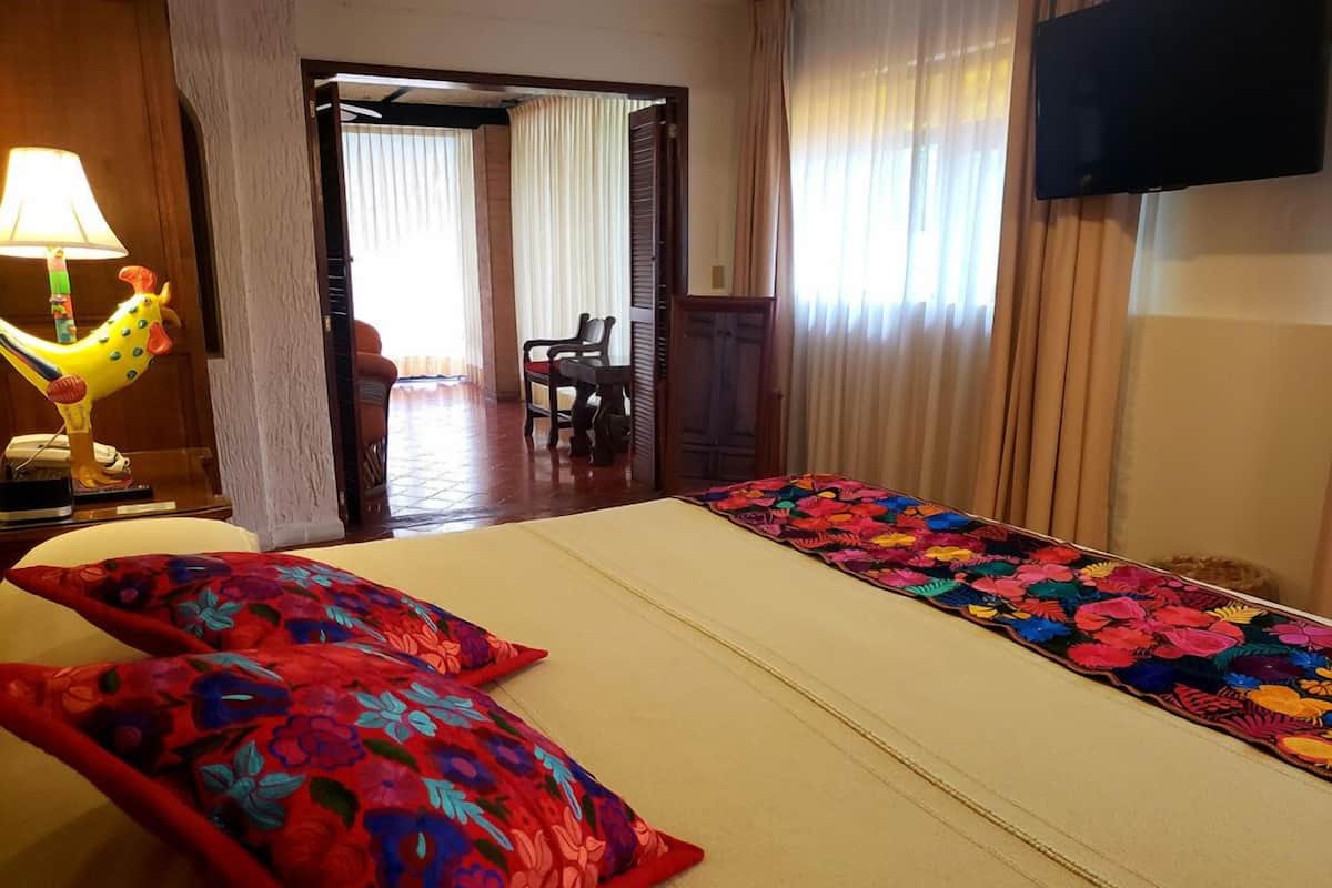 Hotellihuone, jossa on sänky, kaksi tyynyä, lamppu, televisio ja näkymä ulos.