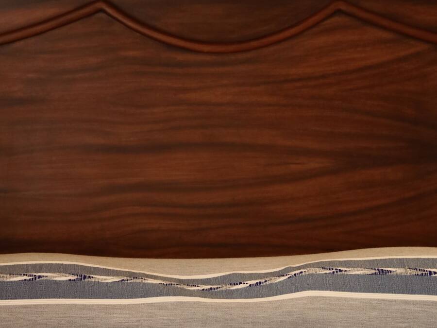 A wooden headboard with a decorative crest and a striped pillow.