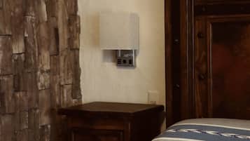 A bedroom with a wooden headboard, a bedside table with a lamp, and a bed with striped bedding.