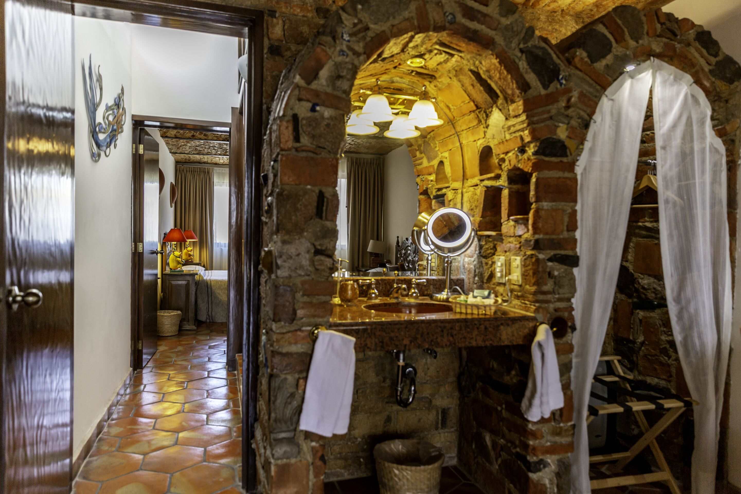 A bathroom with a stone arch, a sink with a mirror, and a towel rack.