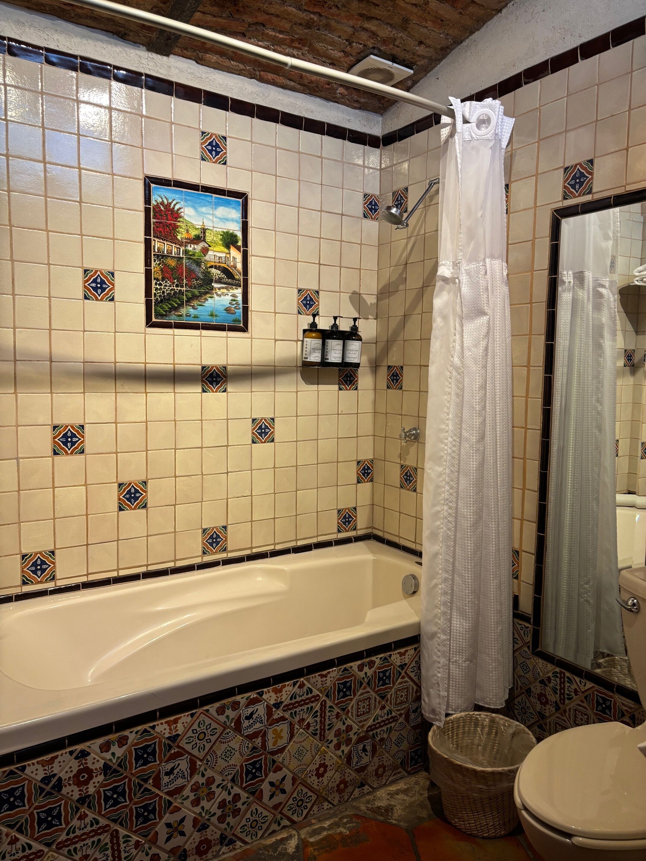 A bathroom with a bathtub, a shower curtain, a toilet, and a sink with toiletries.
