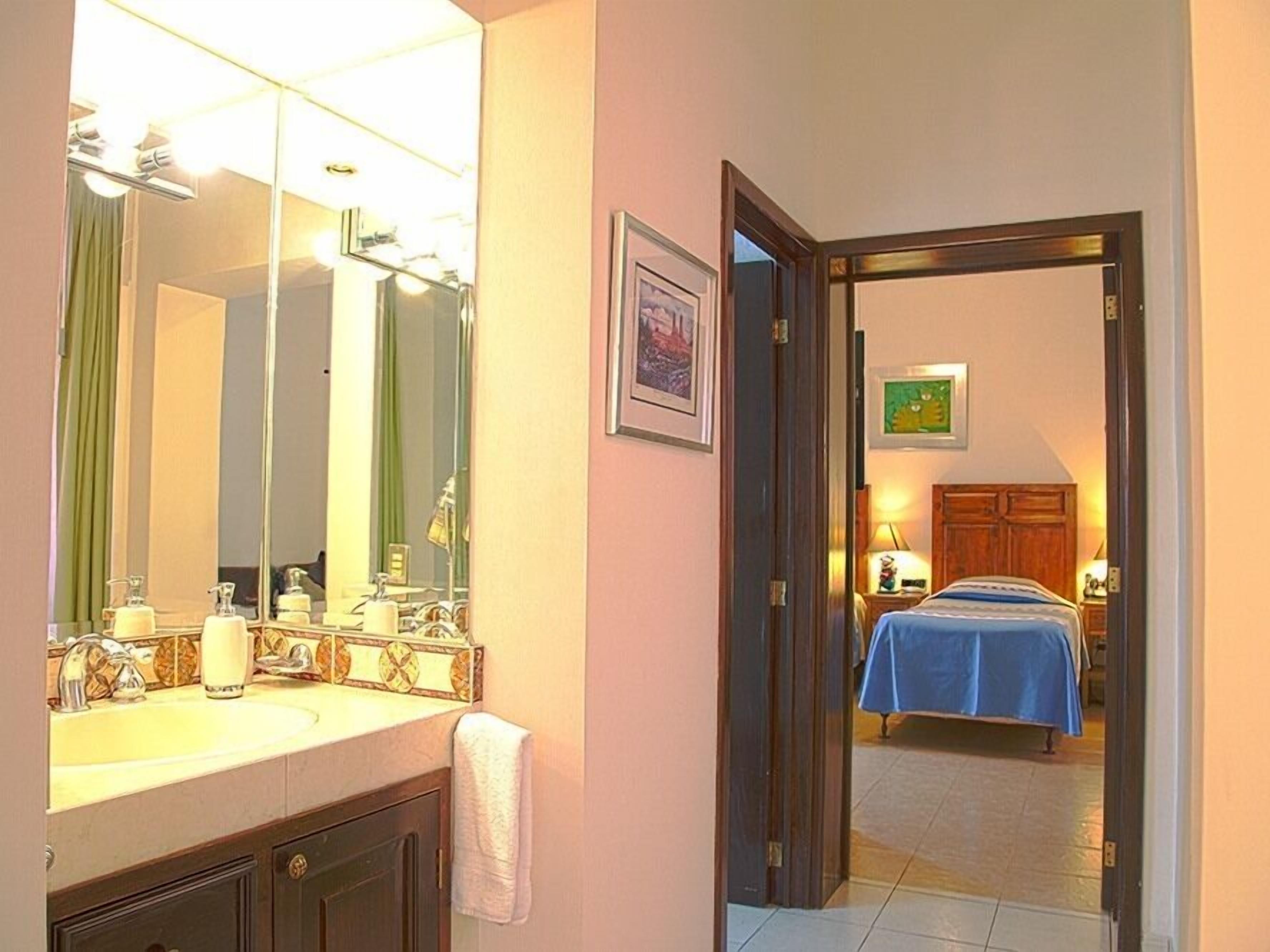 A hotel bathroom with a large mirror, a sink, and a towel hanging on the wall.
