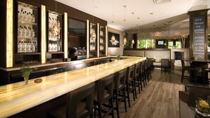 A bar area with a long counter, multiple bar stools, and a variety of bottles and glasses on shelves. - Hockley Valley Resort (Mono)