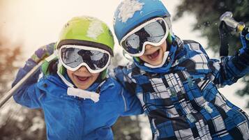 Dos niños esquiando, usando casco y gafas, en un entorno nevado.