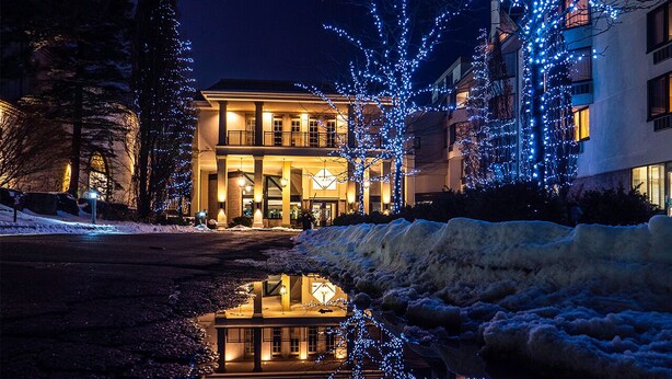 A building with a reflective pool in front, surrounded by snow and illuminated by blue lights. - Hockley Valley Resort (Mono)