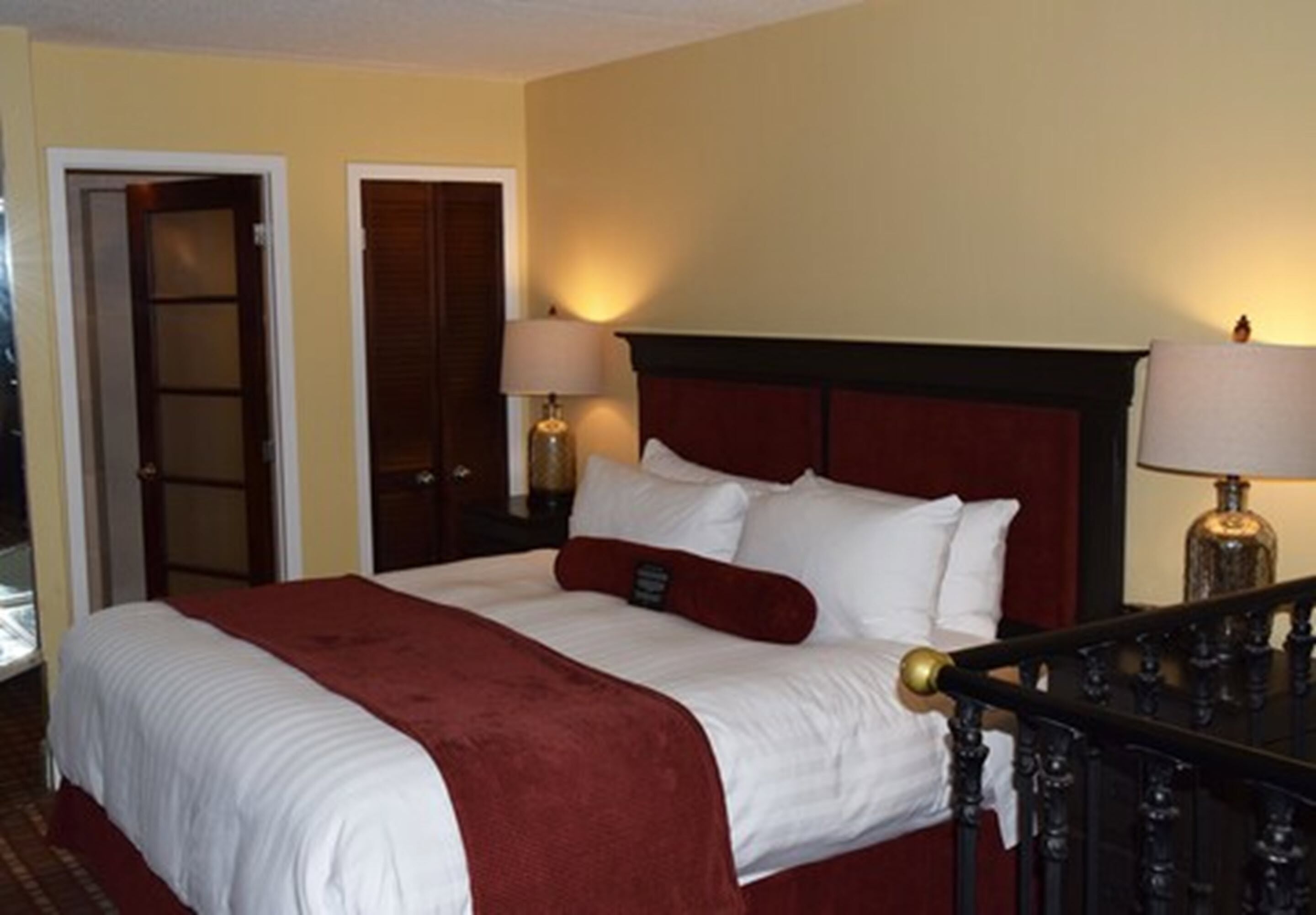 Een hotelkamer met een groot bed, twee bedlampen en een rode hoofdbord.