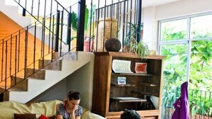 A living room with a wooden coffee table, a sofa, and a staircase with a railing. - Hostal San Pancho - Hostel (San Francisco)