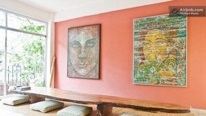 A room with a long wooden bench, cushions, and two large artworks on the wall. - Hostal San Pancho - Hostel (San Francisco)