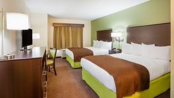 A hotel room with two beds, a desk, a chair, a television, and a window with curtains.