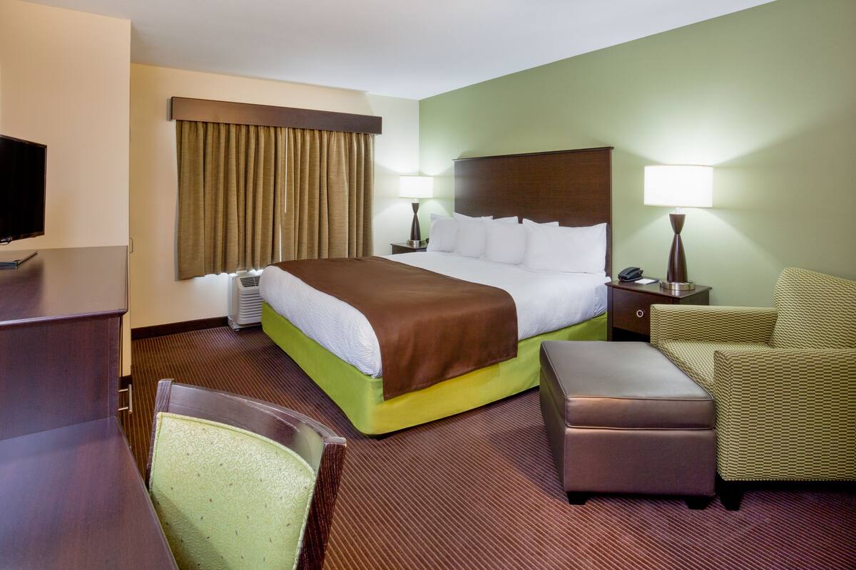 Ein Hotelzimmer mit Bett, Schreibtisch, Stuhl, Fernseher und Lampe.