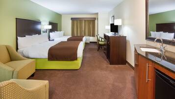 Ein Hotelzimmer mit einem großen Bett, einem Schreibtisch, einem Sessel, einer Couch und einem Badezimmer mit Waschbecken und Spiegel.
