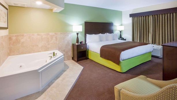 A hotel room with a large bed, a separate bathroom with a bathtub, and a seating area.