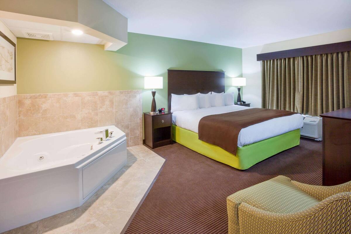 Ein Hotelzimmer mit einem großen Bett, einem eigenen Badezimmer mit einer Badewanne und einer Sitzecke.