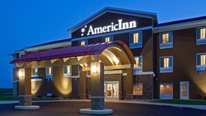 A multi-story American Inn with a prominent sign, a covered entrance, and a landscaped driveway.