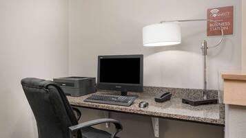 A business station with a desktop computer, keyboard, mouse, and a lamp.