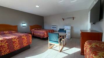 A hotel room with two beds, a desk, a chair, a TV, and an air conditioning unit.