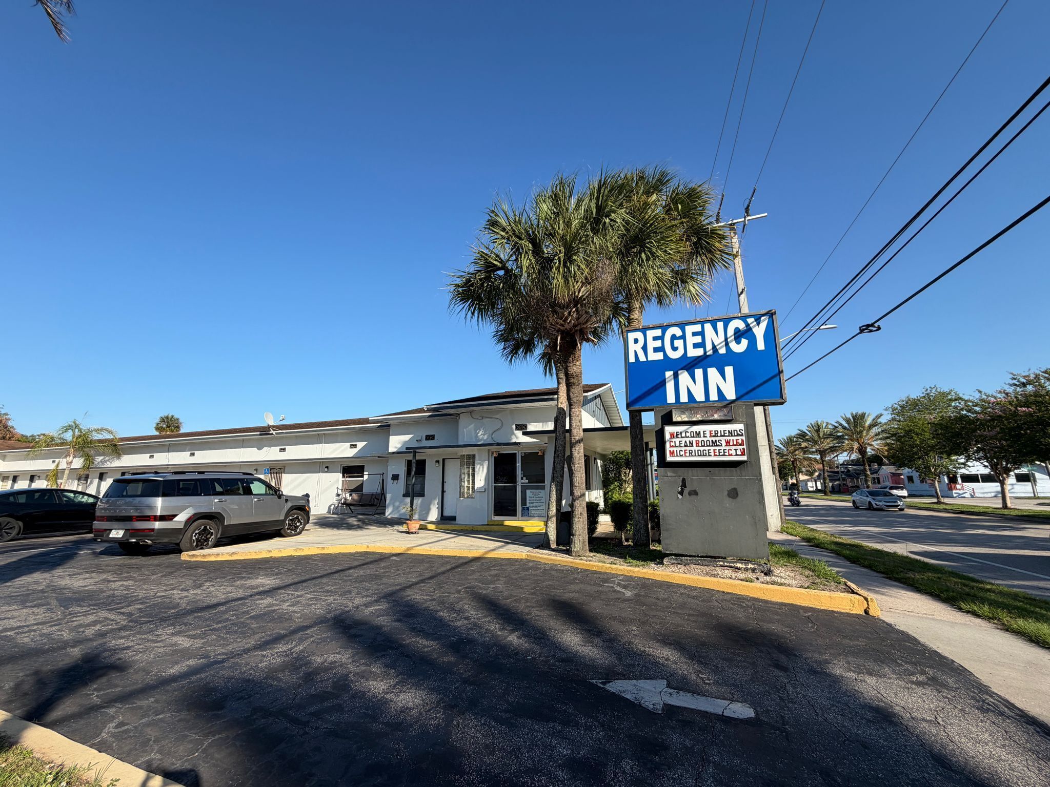 Un edificio con un letrero que dice 'REGENCY INN' y un estacionamiento con coches.