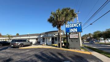 Un edificio con un letrero que dice 'REGENCY INN' y un estacionamiento con coches.