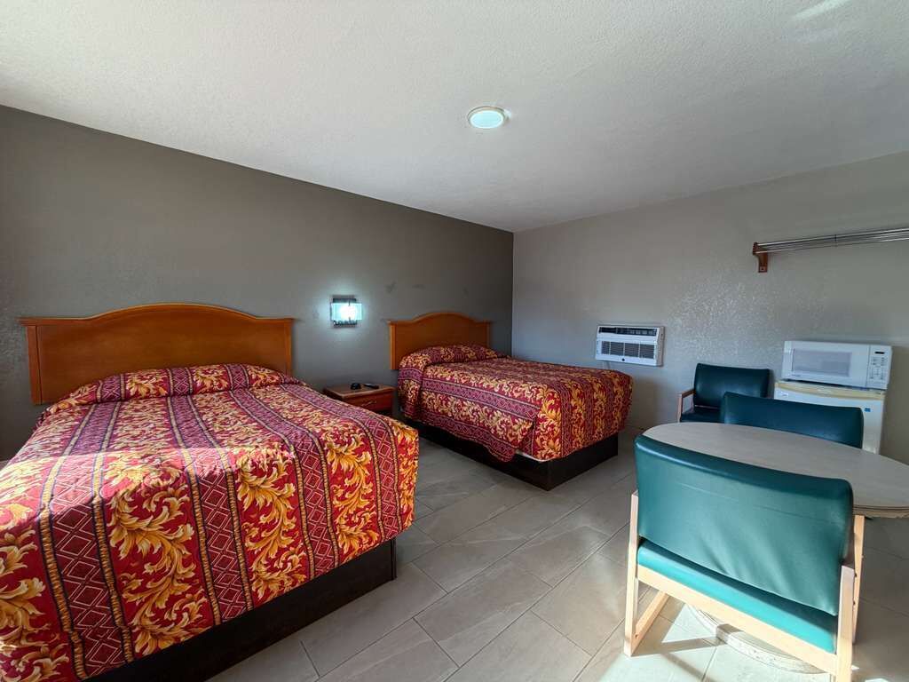 Une chambre d’hôtel avec deux lits, un bureau et un four à micro-ondes.