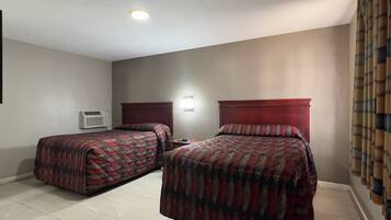 A room with two beds, a ceiling light, a wall-mounted air conditioner, and a green chair.