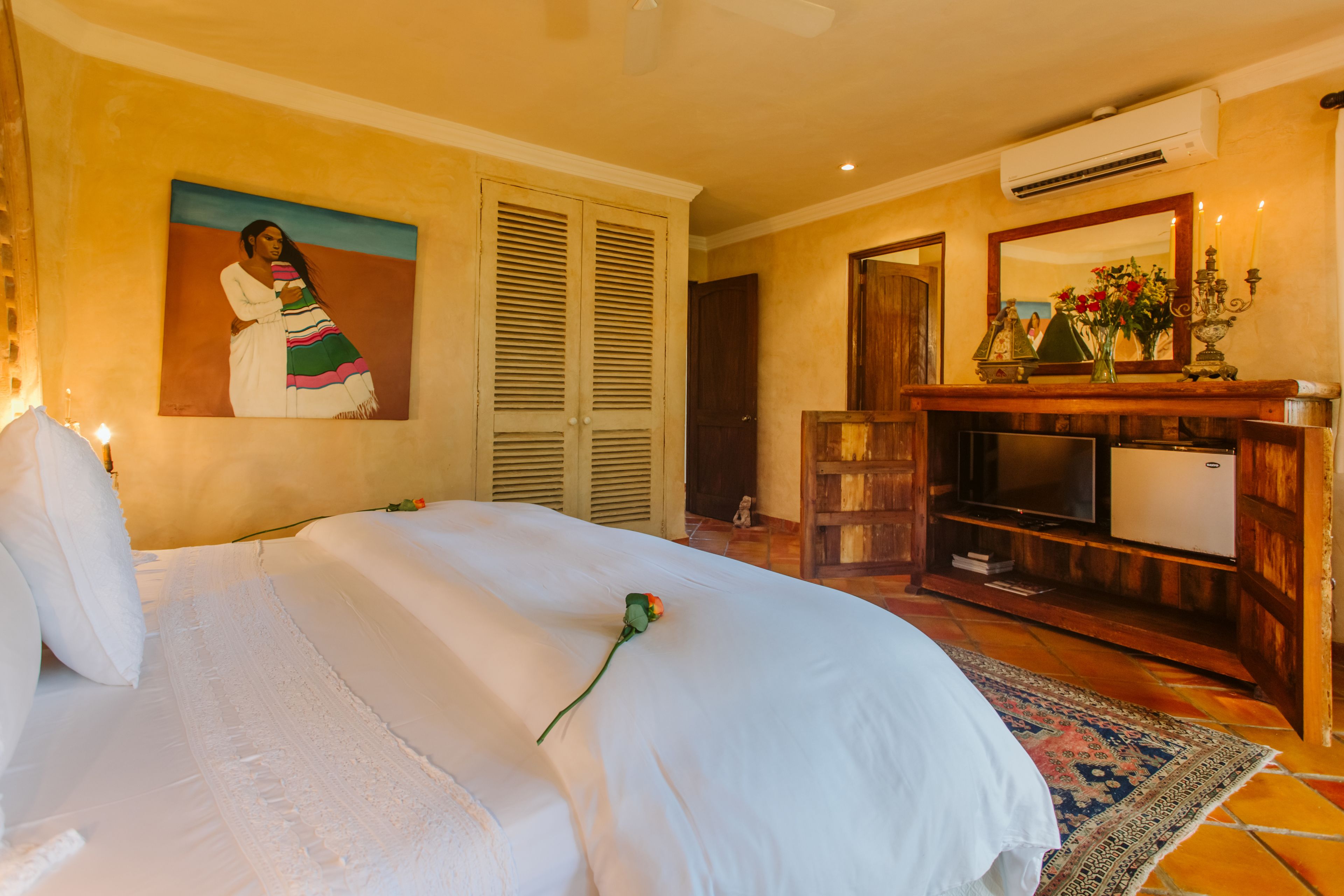 Una habitación de hotel con cama, un cuadro, un aparador y un equipo de aire acondicionado.