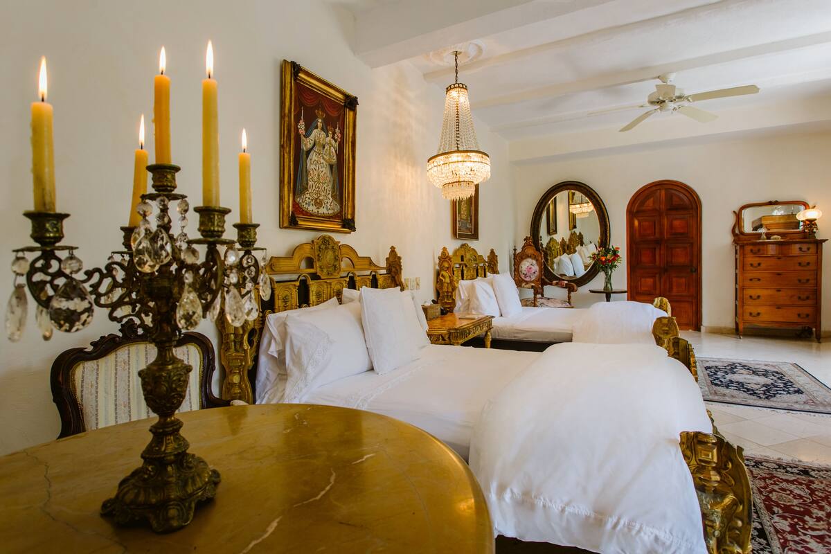 Een luxueuze slaapkamer met sierlijk meubilair, een kroonluchter en een grote spiegel.