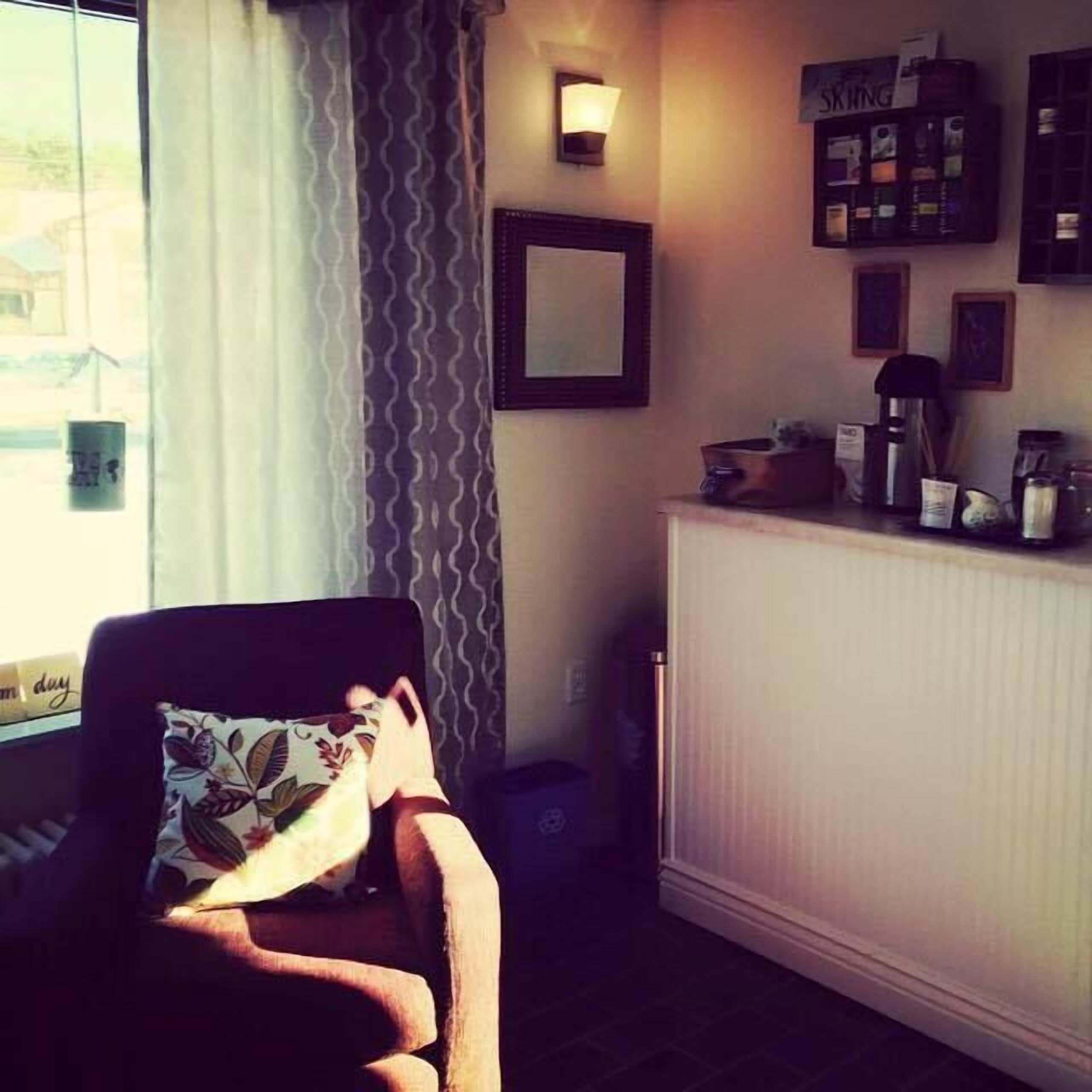 A cozy room with a chair, a radiator, a coffee machine, and a wall-mounted sign.
