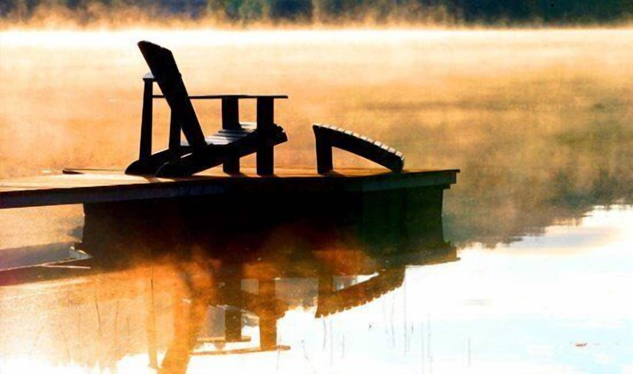 Un muelle de madera que se adentra en aguas tranquilas, con una silla y un banco.