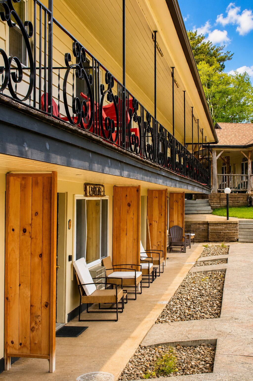 Een hotel met een overdekt terras, houten deuren en een balkon met metalen hekwerk.