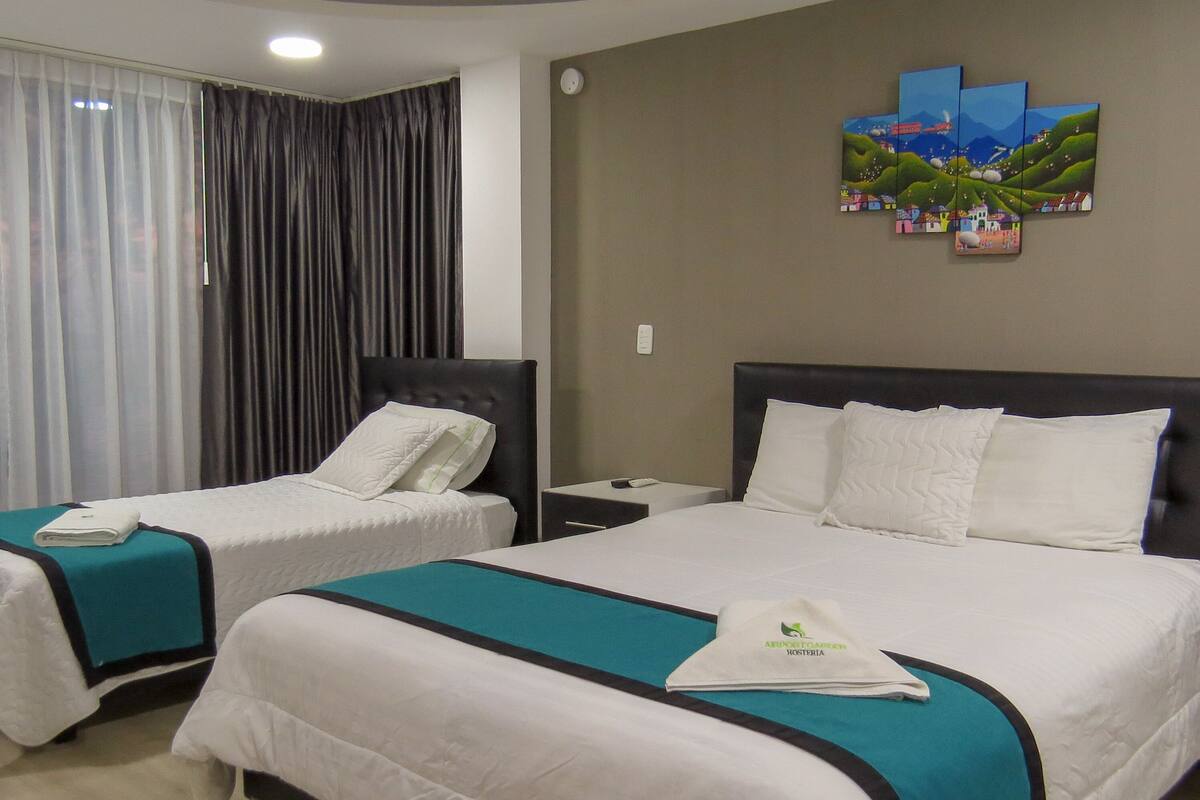 Una habitación de hotel con dos camas, una mesita de noche, un reloj y un cuadro en la pared.