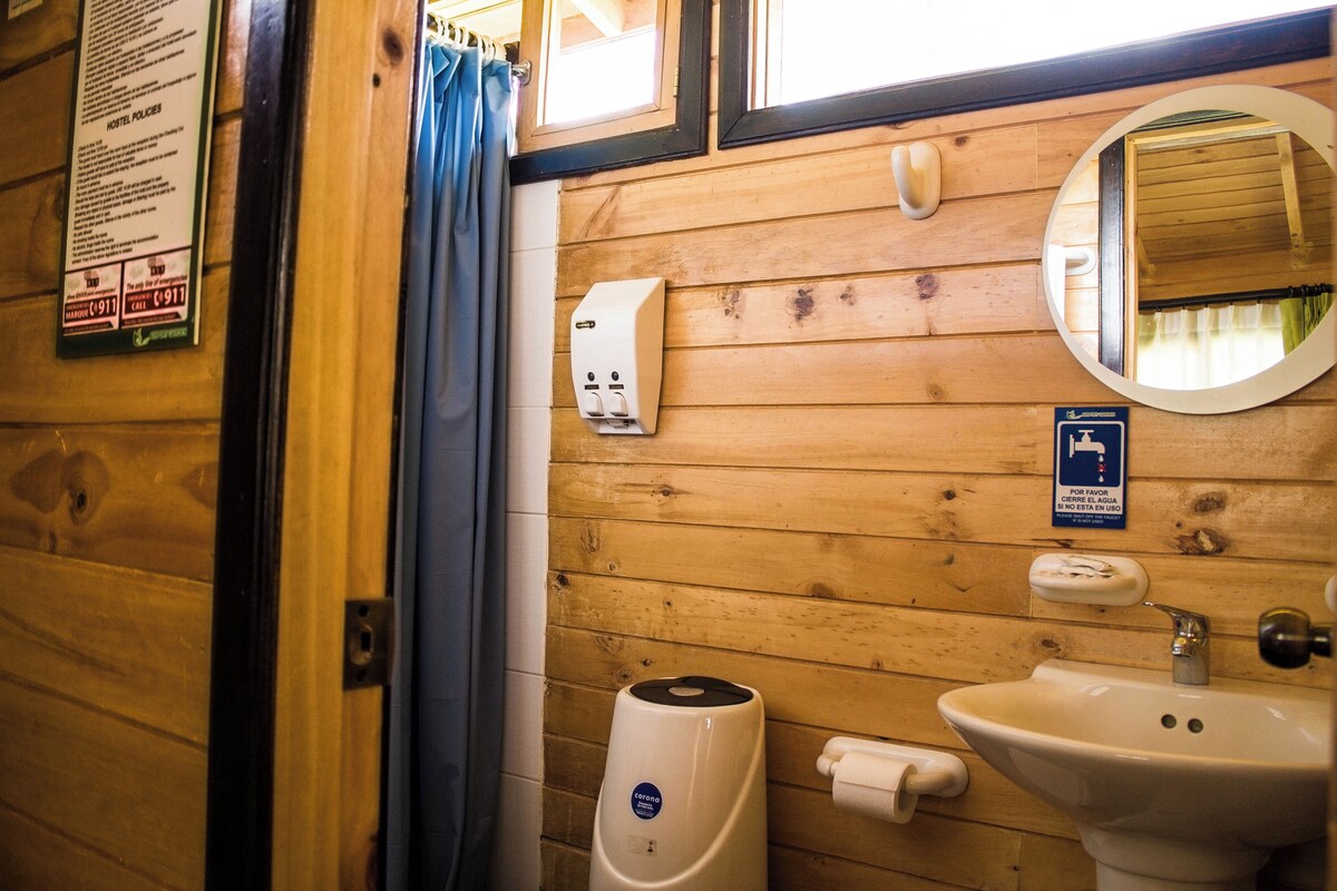 A wooden interior with a sink, hand dryer, and a mirror.